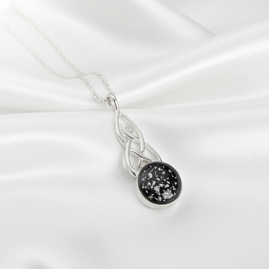 Round Celtic Drop Memorial Ashes Necklace made using black resin and displayed on white satin - Nicky Robin Memorial Jewellery