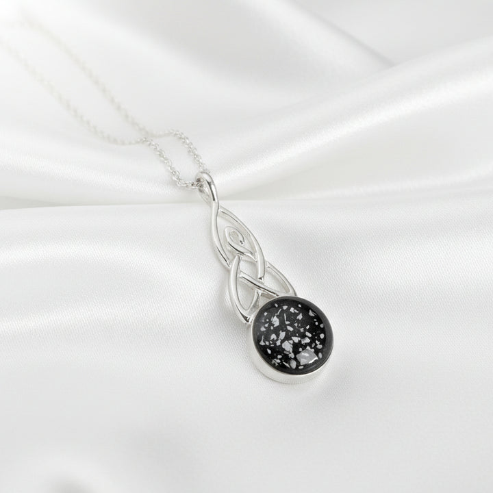 Round Celtic Drop Memorial Ashes Necklace made using black resin and displayed on white satin - Nicky Robin Memorial Jewellery