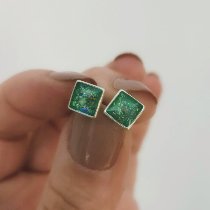 Holding square memorial ashes earrings to showcase