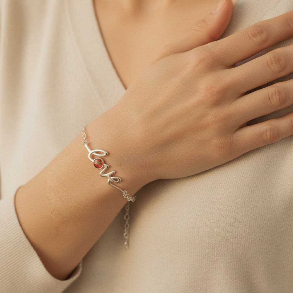 Model wears love word bracelet. A pretty font created into the word love, with the letter O solid and made with a resin setting to hold ashes.